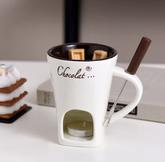 Beige fondue mug showing its lower candle compartment and utensil holder beside the handle